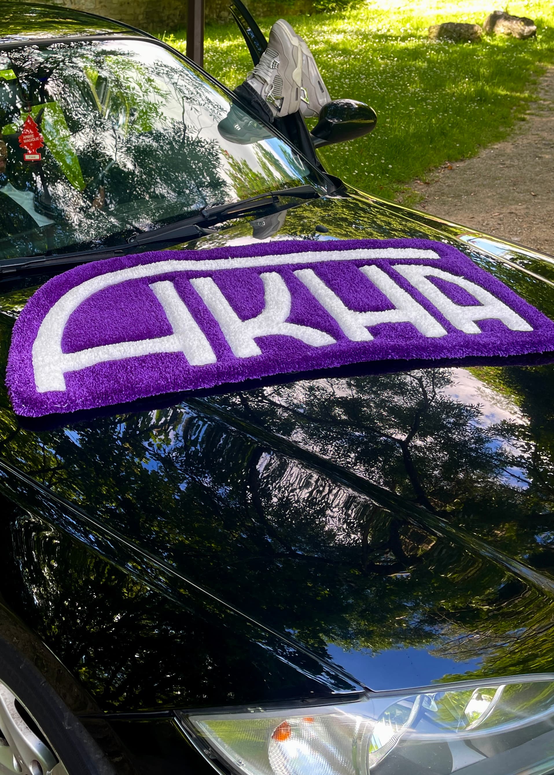 Tapis à l'effigie du logo AKHA sur le capot d'une voiture